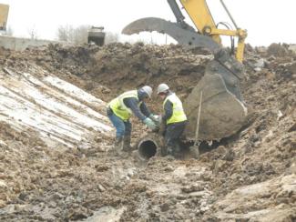 UXO Technicians inspect and prepare for removal of contaminated pipe.